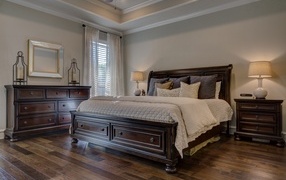 Дорогая деревянная кровать в спальной комнате