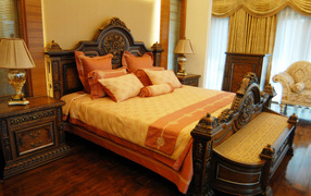 Большая деревянная кровать в спальне с оранжевым интерьером