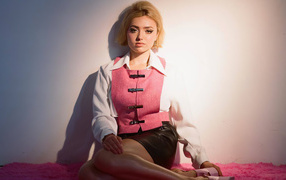 Молодая девушка Пейтон Рой Лист сидит у стены