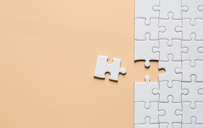 Белый пазл собирают на бежевом фоне