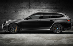 Вид сбоку на черный автомобиль BMW M5 Touring 2024 года