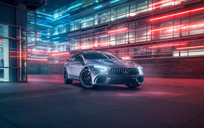 Серебристый автомобиль Mercedes AMG GT4 на фоне здания