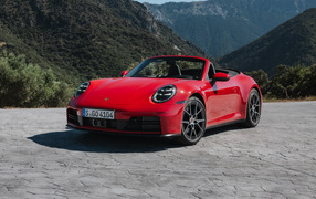 Красный Porsche 911 Carrera Cabriolet 2024  года на фоне гор