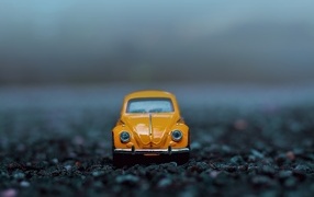 Маленькая игрушечная машинка стоит на асфальте