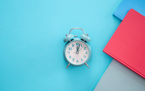 Будильник с книгами на голубом фоне