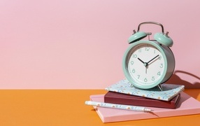 Будильник с книгами на розовом фоне
