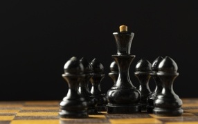 Черные шахматные фигуры на доске на черном фоне