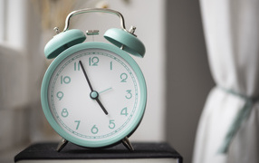 Голубой будильник стоит на книге в комнате