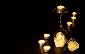 Зажженные свечи с цветами розы на черном фоне