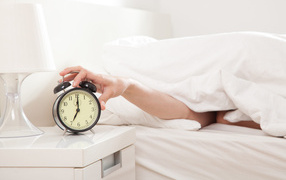 Рука под одеялом отключает будильник