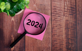 Увеличительное стекло с листом бумаги и цветком на столе