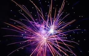 Разноцветные сиреневые искры фейерверка на черном фоне