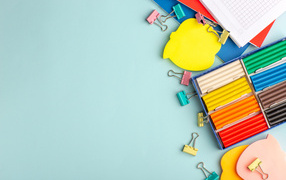 Пластилин на голубом фоне со скрепками и блокнотами