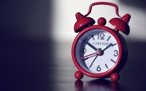 Красный будильник на черном столе