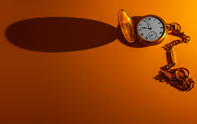 Тень от карманных часов на оранжевом фоне