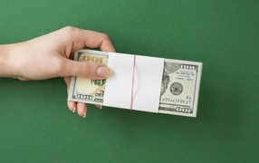 Пачка денег в руке у девушки на зеленом фоне