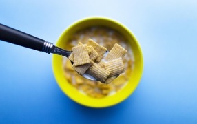 Хлопья с молоком на ложке на голубом фоне