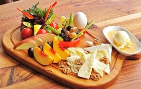 Сыр на доске с фруктами и салатом
