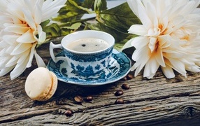 Чашка кофе с макарунами на столе с цветами