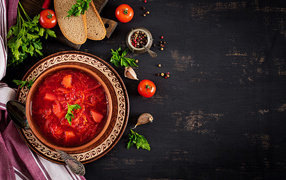 Вкусный красный борщ в тарелке на столе