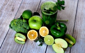 Зеленое смузи с овощами и фруктами на столе