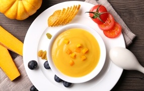 Тыквенный суп пюре на тарелке с картофелем и помидором