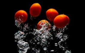 Красные помидоры в воде на черном фоне