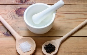 Соль с перцем на столе с деревянной ступкой