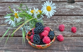 Ягоды черники и малины на столе с ромашками