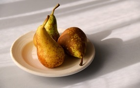 Три груши на тарелке на столе