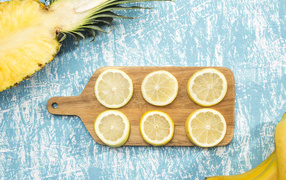 Деревянная доска с лимоном на столе с ананасом