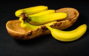Wooden bowl with bananas on the table