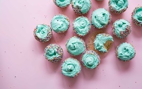 Appetizing cupcakes with blue cream on a pink table