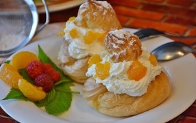 Заварное печенье со взбитыми сливками на тарелке с ягодами