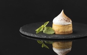 Десерт с кремом и листьями мяты на черном фоне