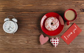 Пончик на столе с будильником, чашкой кофе и сердечками