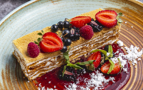 Большой кусок медового торта с ягодами