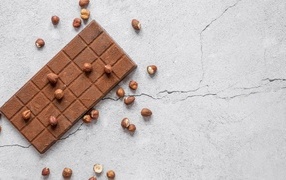 Молочная шоколадка с орехами на сером столе