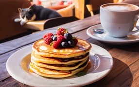 Оладьи с ягодами на столе с кружкой кофе