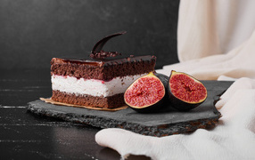 Кусок шоколадного торта с половинками инжира на столе