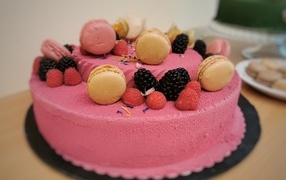 Розовый торт украшен печеньем и ягодами