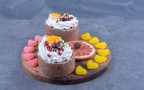 Два пирожных на деревянной доске с мармеладными конфетами