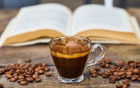 Чашка кофе на столе с зернами и книгой