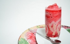 Стакан красного ягодного смузи на столе с чайной ложкой