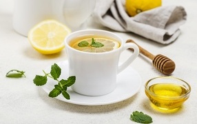 Белая кружка с чаем на столе с медом и лимоном