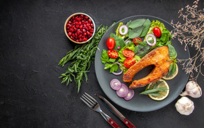 Жареная рыба на тарелке с овощами и зеленью
