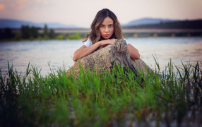 Девушка у воды прячется за камнем