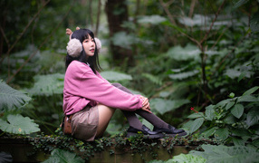 Девушка азиатка в розовом наряде сидит в зарослях