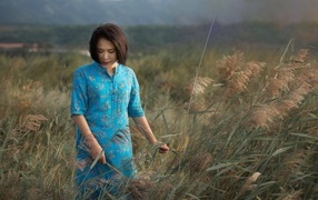 Девушка азиатка в платье на поле с колосьями