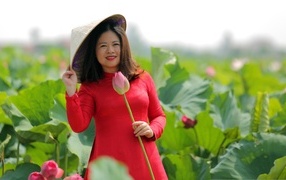 Девушка азиатка в красном платье у цветов лотоса